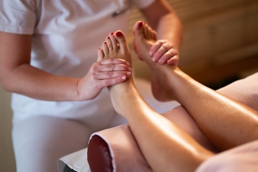 Foot Massage Therapy in a Relaxing Spa Setting. A professional massage therapist in a white uniform provides a soothing foot massage to a client in a calm and serene spa environment photo