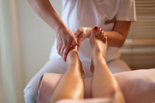Foot Massage Therapy in a Relaxing Spa Setting. A professional massage therapist in a white uniform provides a soothing foot massage to a client in a calm and serene spa environment photo