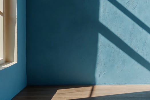 Sunlight streams into a blue room, illuminating a corner and hardwood floor photo