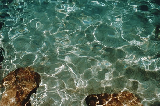 Sunlit turquoise water shimmers above seabed rocks photo