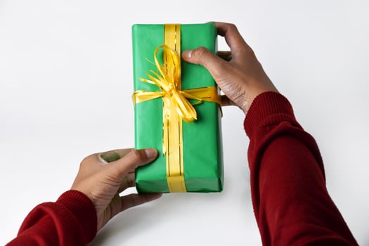 Close-up photo of two hands holding and presenting a green gift box