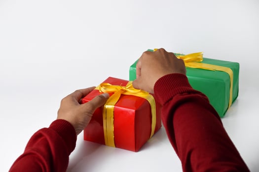 Closeup image of two hands holding a red and a green gift box photo