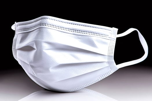 White surgical mask resting on a reflective surface, promoting health and safety photo