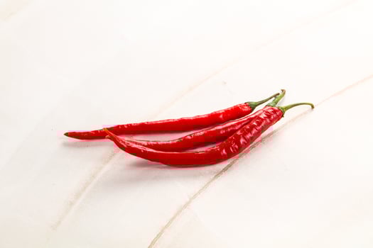 Two red chili peppers on a white surface photo