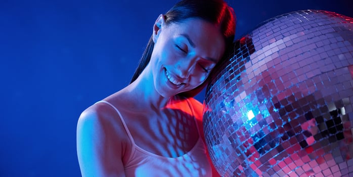 Holding mirrored, ball in the club. Young woman in underwear is in the studio with neon lights photo