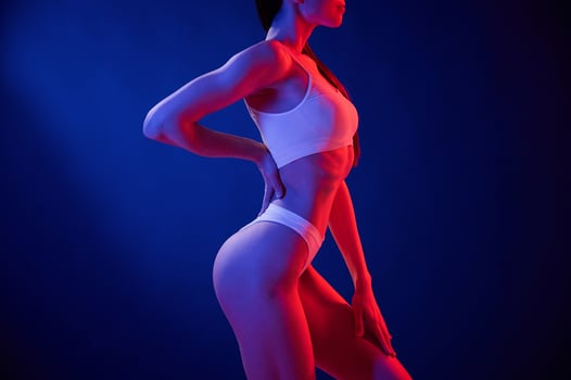Side ,view. Young woman ,in underwear is in the studio with neon lights photo