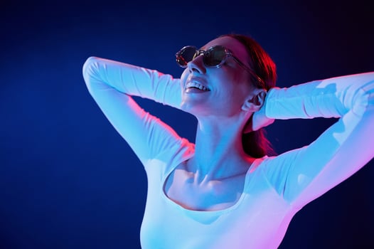 In sunglasses. Portrait of young woman that is indoors in neon lighting photo