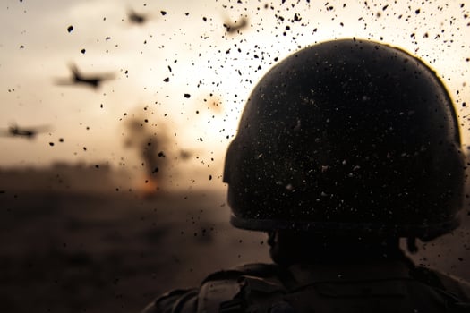 Soldier observing chaos during sunset amidst explosions and debris flying. photo