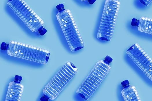 Clear single-use plastic water bottles on light blue background close-up pattern, minimal style aesthetic photo, top view bottled water, Pollution, environmental protection, plastic waste photo