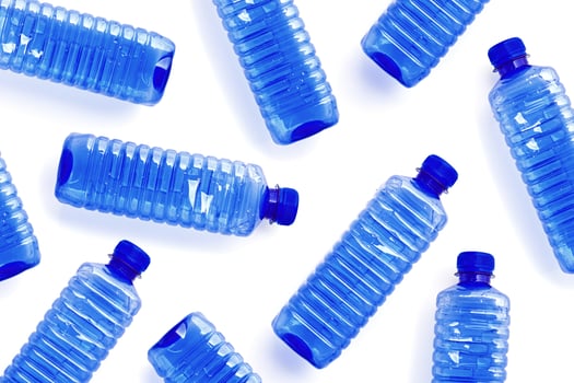 Pattern with blue plastic bottles isolated on white background, top view empty plastic bottle for water half litre, minimal style design. Pollution, plastic garbage, environmental protection concept photo