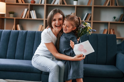 Embracing ,each other. Giving the gift. Young mother with her daughter is together at apartment photo