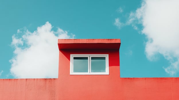 A striking red wall with a white window against a vivid blue sky. photo