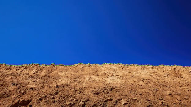 A clear blue sky above a textured, dry earth surface. photo