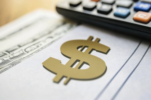 A calculator sits on top of a check with a dollar sign on it photo