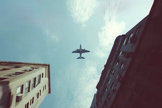 Airplane flying over buildings in urban cityscape photo