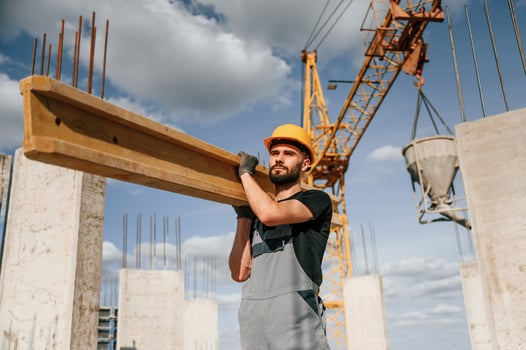 Front view ,of man that is in uniform holding ,wooden plank on the construction site photo