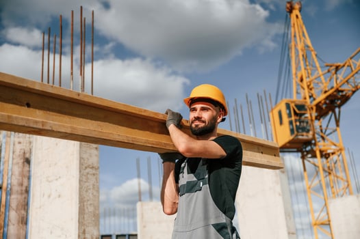 Holding and walking ,with wooden plank. Man in uniform is working on the construction site photo
