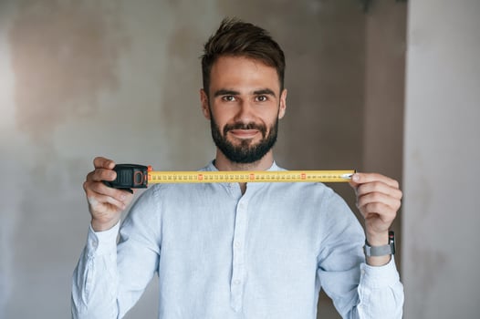 Holding ruler measurement tool. The man is making repairs in the apartment photo