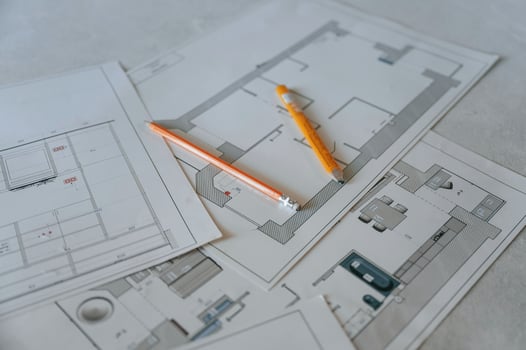 Close up view of plan of building repaiting and contruction that is on the floor with yellow pencils on it photo