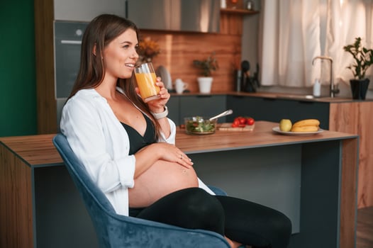 With ,orange juice.. Beautiful pregnant woman is indoors at home photo