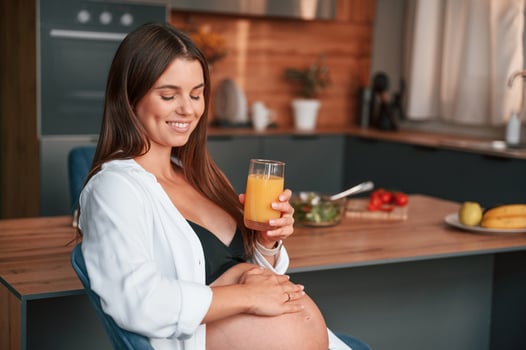 With orange juice. Beautiful pregnant woman ,is indoors at home photo