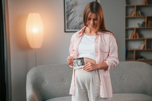 Holding,ultrasound diagnostics ,picture of the baby. Beautiful pregnant woman is indoors at home photo