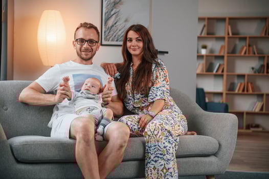 On the sofa together. Happy couple with their newborn boy is at home photo