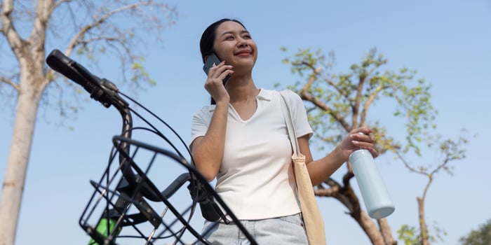 Sustainable Living and Connectivity. A woman talking on the phone while holding a reusable water bottle, embodying an eco-conscious lifestyle. photo