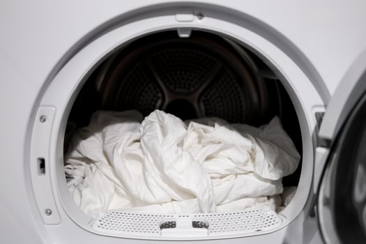 White bedsheets in modern tumble dryer close up laundry scene photo