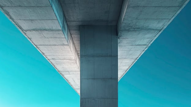 Looking Up at Concrete Bridge Support Against Blue Sky Background photo