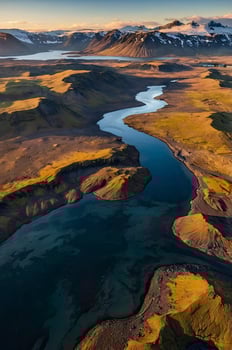 Aerial View of River Winding Through Icelandic Landscape with Snow Mountains photo