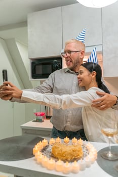 Here's a title attempting to follow your specifications. Couple Birthday Cake Selfie Kitchen Celebration. Happy couple takes birthday selfie with cake in kitchen celebrating. photo