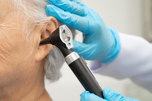 Otolaryngologist or ENT physician doctor examining senior patient ear with otoscope hearing loss problem. photo