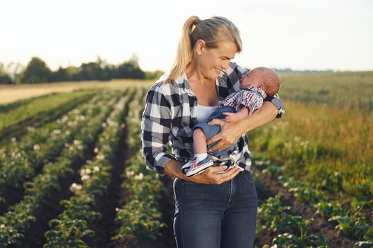 Standing and ,smiling, Happy woman on the agricultural field is with little baby in the hands photo