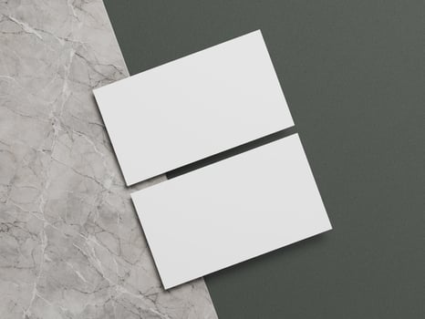 Elegant business card mockup with clean white cards positioned diagonally over a marble and dark green surface. photo