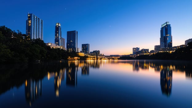 A vibrant skyline of Austin showcases modern skyscrapers illuminated against a night sky. The serene lake below beautifully reflects the architectural outlines and city lights photo