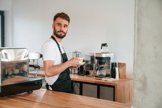 With, cup of ,coffee. Cafe worker in white shirt and black apron is indoors photo