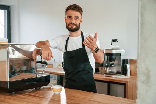 Beautiful portrait. Cafe worker in white shirt and black apron is indoors photo