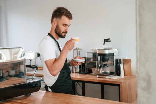 With, cup ,of coffee. Cafe worker in white shirt and black apron is indoors photo