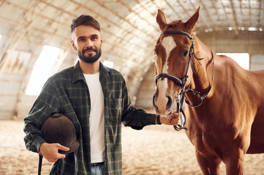 Positive emotions.. Front ,view. Young man with a horse is in the hangar photo