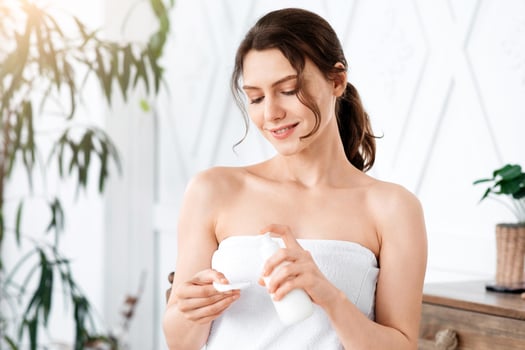 Beautiful girl cleaning makeup with face lotion at home, applying product on cotton pad, copy space photo