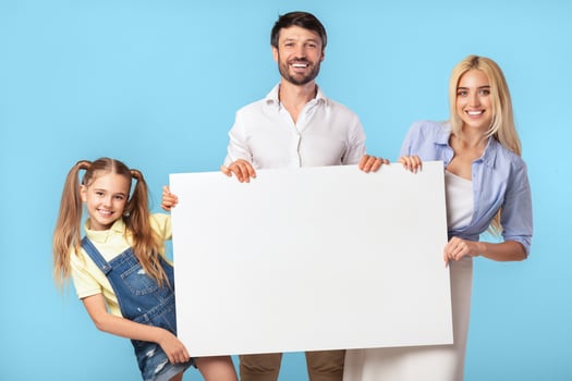 Family Offer. Parents And Daughter Holding Blank Board Over Blue Studio Background. Mockup, Copy Space photo
