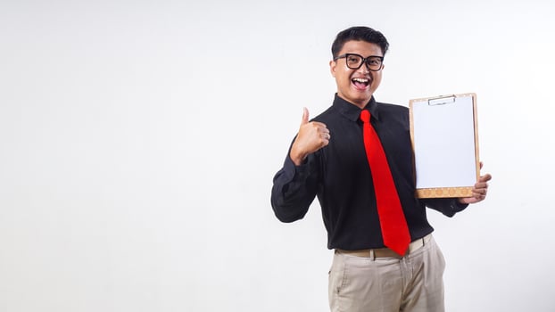 Confident Asian employee businessman corporate wearing formal clothes holding wooden clipboard with blank paper copy space and showing thumb up isolated on white background photo