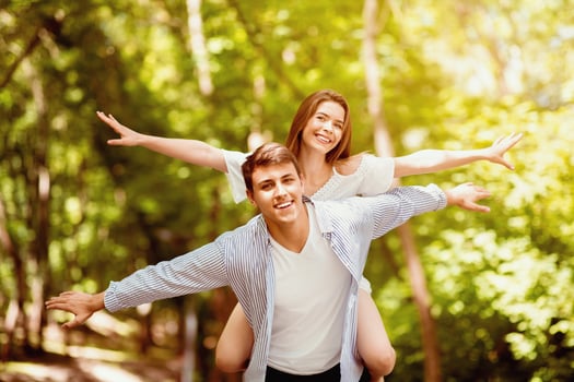 Young loving coupe at park. Boyfriend carrying his girlfriend on his back outdoors photo