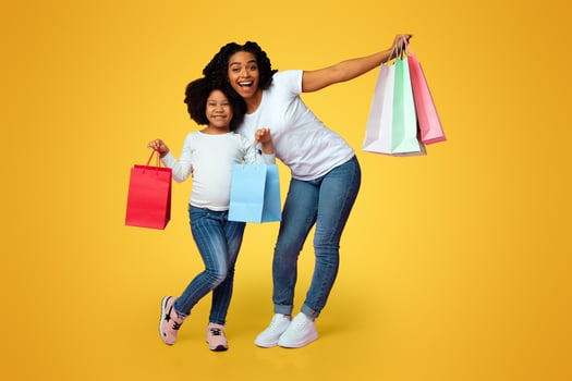 Seasonal Sales. Happy Black Mother And Daughter Posing With Bright Shopping Bags, Standing On Pink Background In Studio, Free Space photo
