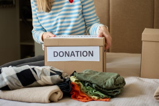 Woman holds donation box filled with clothes on bed photo