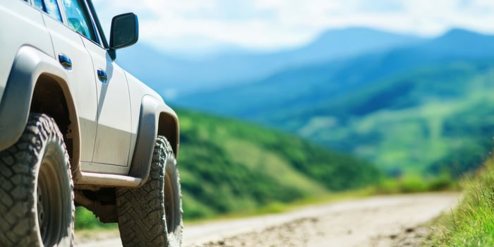 Off road vehicle on mountain road with lush green hills and blue sky adventure travel concept photo