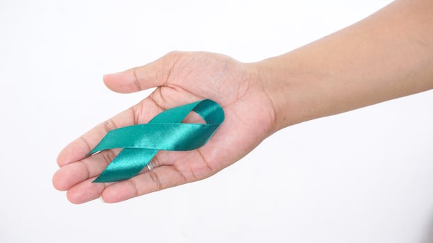 Green awareness ribbon in man hand isolated on white background photo
