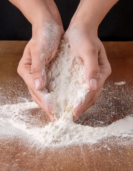A person's hands are holding a bowl of flour photo