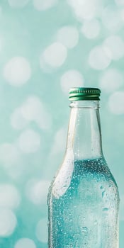 Refreshing glass bottle with water droplets and blue bokeh background photo